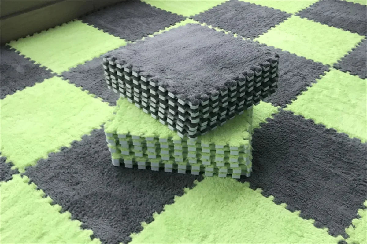 A stack of gray interlocking puzzle rug mats on a green and gray checkered floor.