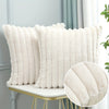 A close-up of a white faux fur pillow cover displayed on a gold-toned table.