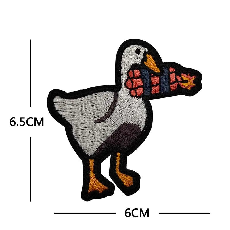 A black and white embroidery patch of a duck with orange beak and feet.