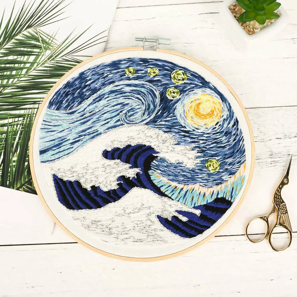 A cross stitch embroidery kit featuring a canvas depicting a blue and white ocean wave under a starry night sky.