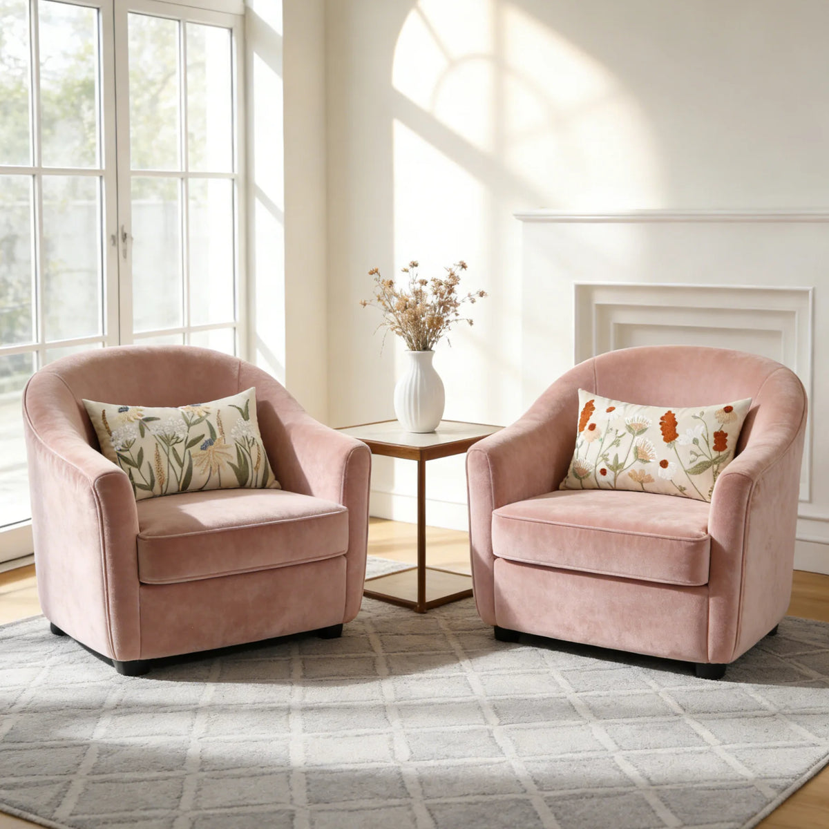 Two pink upholstered armchairs with floral embroidered throw pillows sit near a bright window.