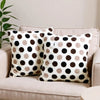 Two throw pillows with a brown and white polka dot pattern resting on a light-colored sofa.