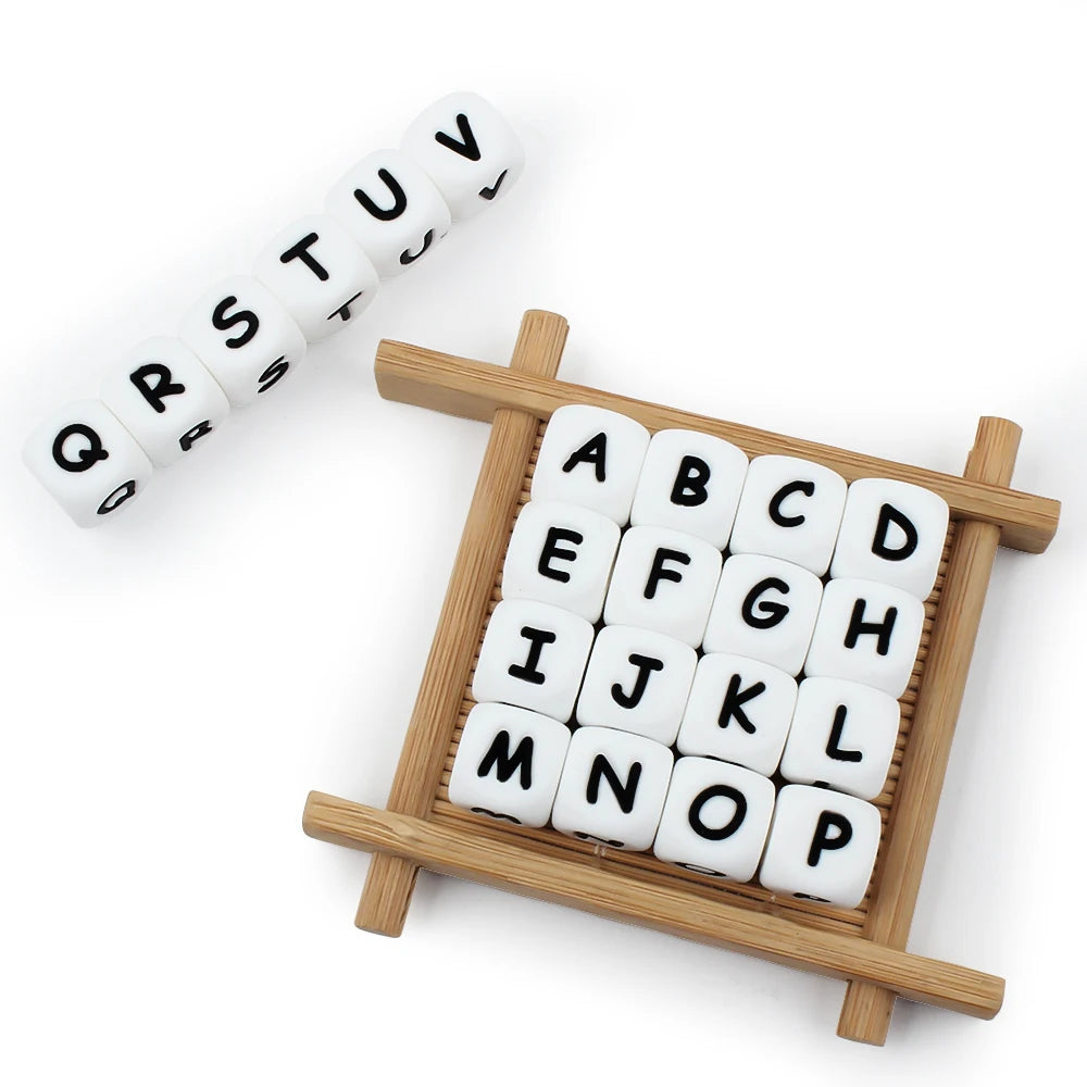 A wooden tray holds a grid of white silicone alphabet beads for DIY jewelry and crafts.