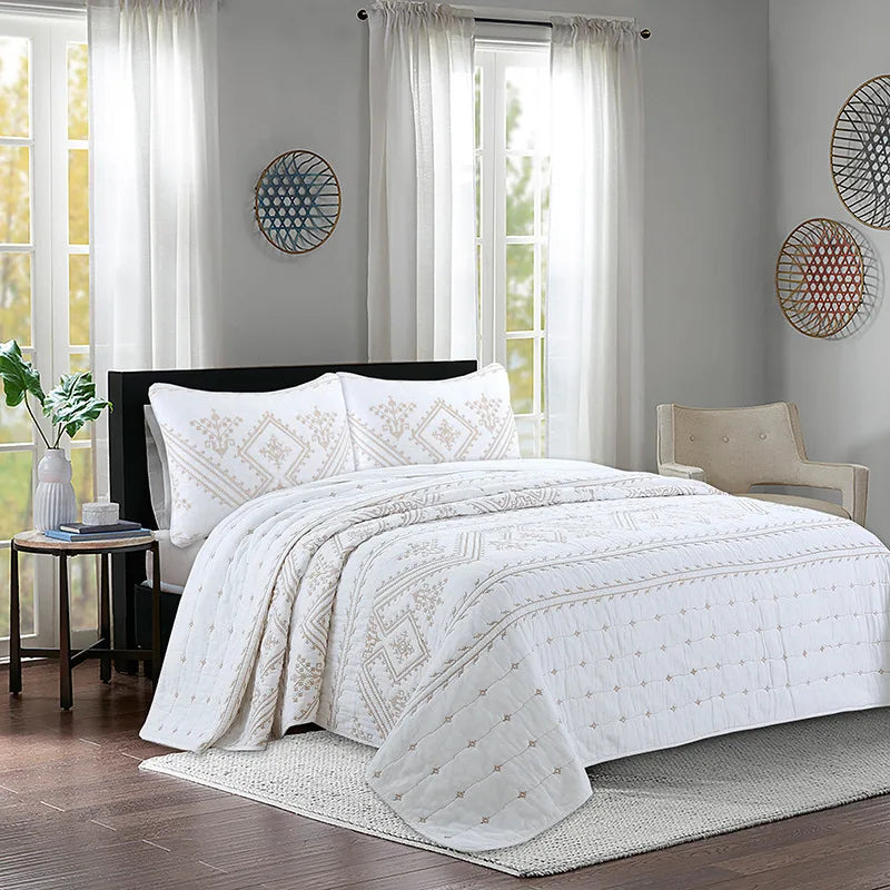 White embroidered bedding set with sheer curtains and natural light in a bedroom setting.