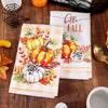 A set of two Hello Fall kitchen towels featuring pumpkin and plaid designs on a wooden surface.
