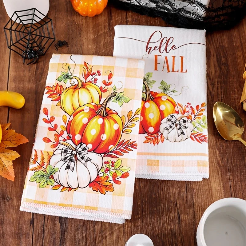 A set of two Hello Fall kitchen towels featuring pumpkin and plaid designs on a wooden surface.