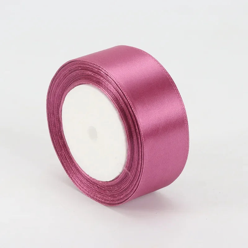 A roll of 4cm satin ribbon in a dusty rose color for crafts and gift wrapping.