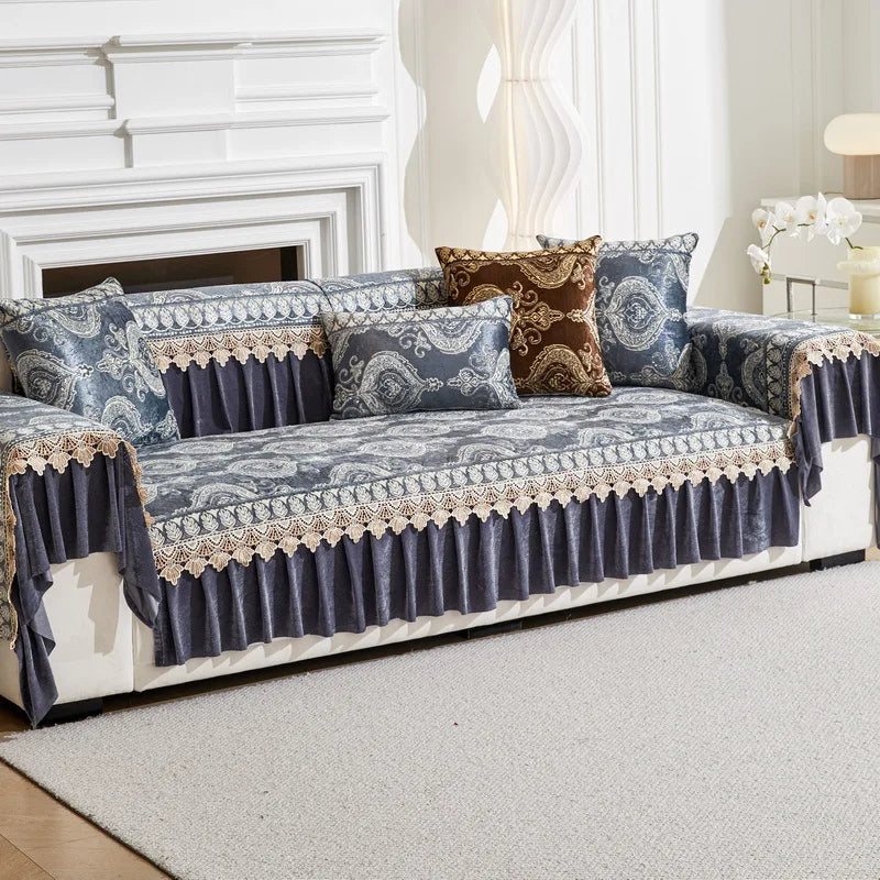 A gray quilted sofa cover with blue and gold patterned fabric and decorative trim on a white sofa.