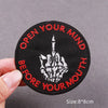 Black embroidered patch with red text Open Your Mind Before Your Mouth featuring a hand gesture