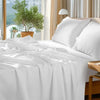 White luxury Egyptian cotton bedding set on a bed with natural light and greenery visible outside