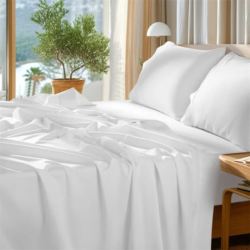 White luxury Egyptian cotton bedding set on a bed with natural light and greenery visible outside