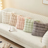 A collection of fluffy, pastel-colored cushion covers displayed on a white sofa.