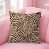 A decorative pillow cover with a brown and beige leopard print pattern resting on a pink sofa.