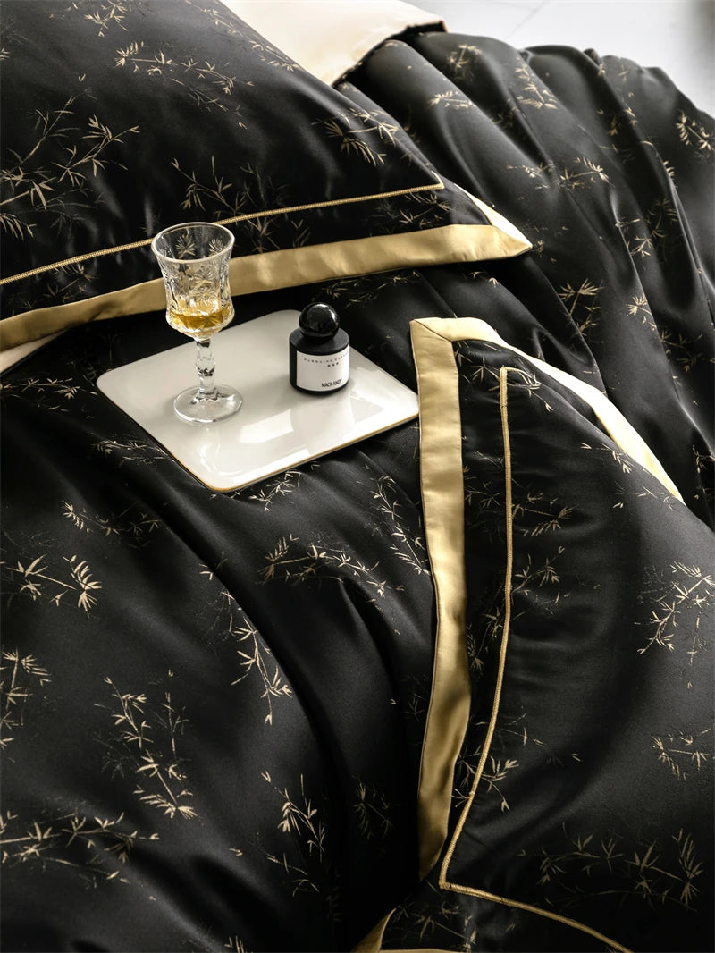 A luxury lyocell eucalyptus bedding set featuring black fabric with gold trim, a glass, and a small dark bottle on the bed.