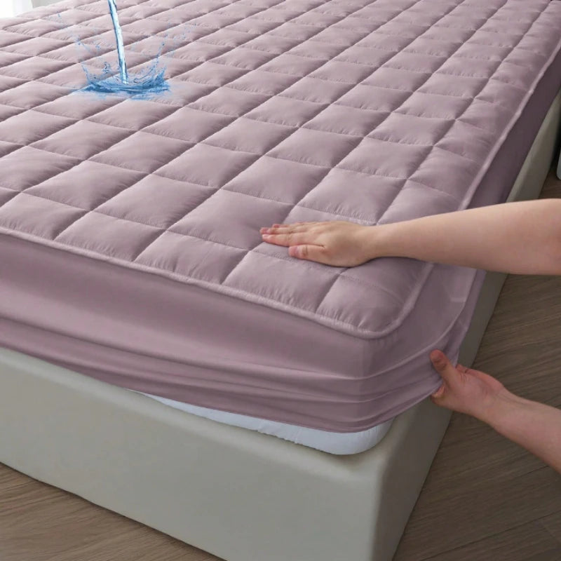 A hand is touching a quilted pink waterproof mattress protector on a bed.