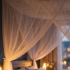 A sheer white mosquito net bed canopy draped over a bed, creating a soft, romantic atmosphere.