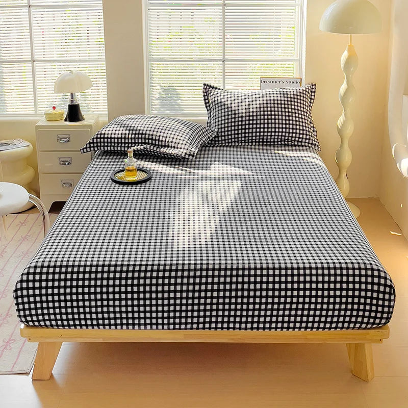 A black and white checkered flannel fitted sheet is laid out on a wooden bed frame.