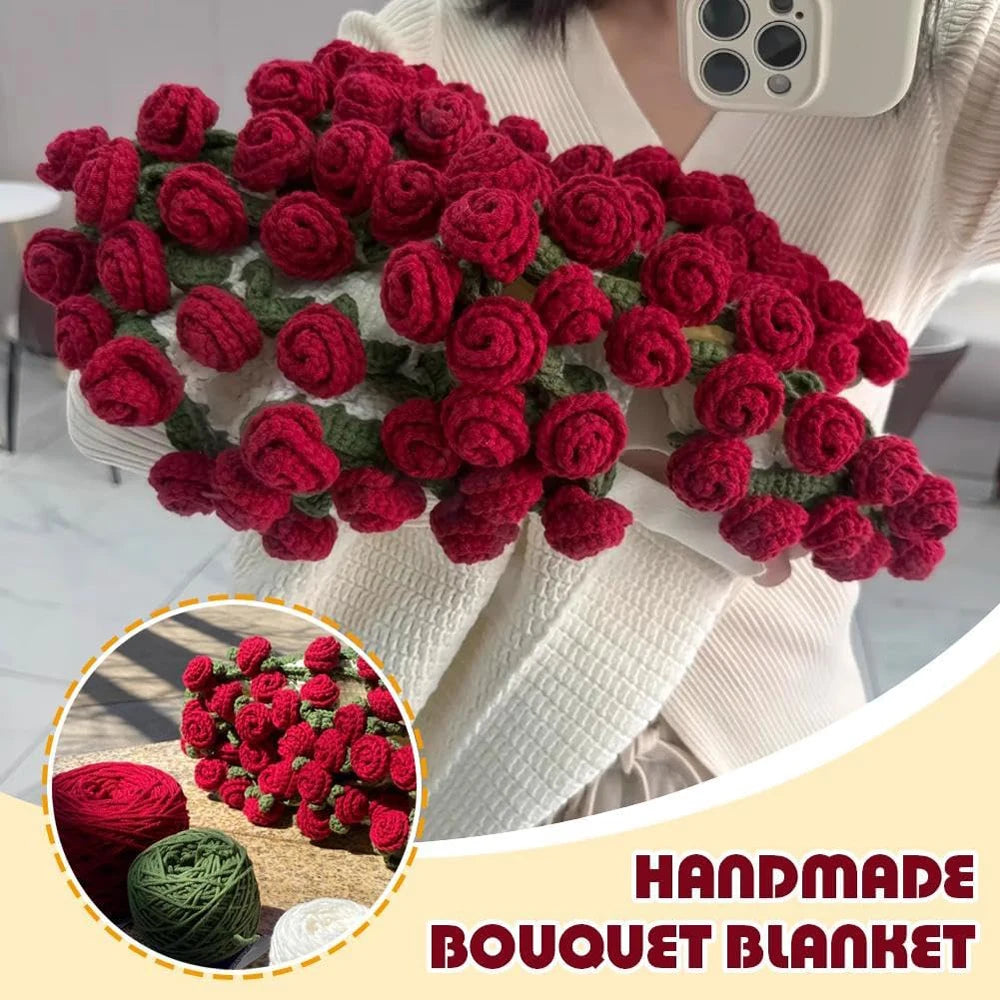 A handmade floral bouquet knitted throw blanket in deep red and green colors is displayed on a person's white sweater.
