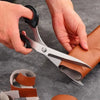 Hands are using professional heavy duty fabric scissors to cut leather material for sewing and tailoring.