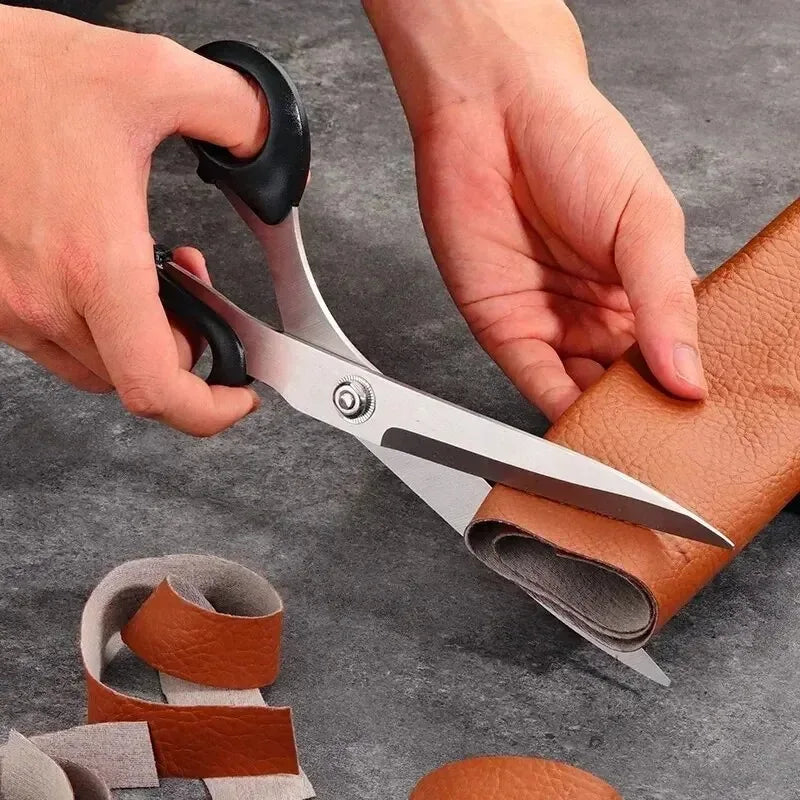 Hands are using professional heavy duty fabric scissors to cut leather material for sewing and tailoring.