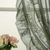 A close-up of sheer moss green lace curtains draped in a window, with a bouquet of pink and yellow roses visible below.