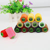 A collection of various colored and sized sewing threads in spools, with a potted green plant in the background.