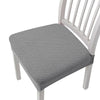 A gray quilted removable polyester bar and dining seat cover placed on a white wooden chair.