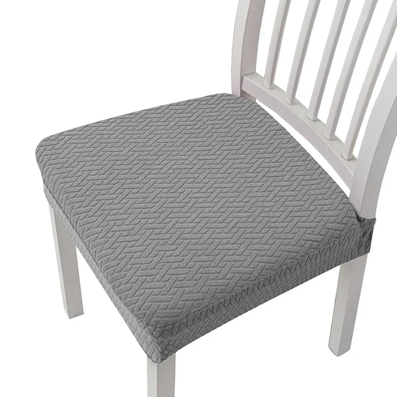 A gray quilted removable polyester bar and dining seat cover placed on a white wooden chair.