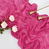A vibrant pink ruffled gauze table runner with gold-toned accents and light pink flowers.
