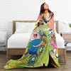 A woman smiling while lying on a bed with an adventure cartoon throw blanket featuring characters like Buzz Lightyear and oth