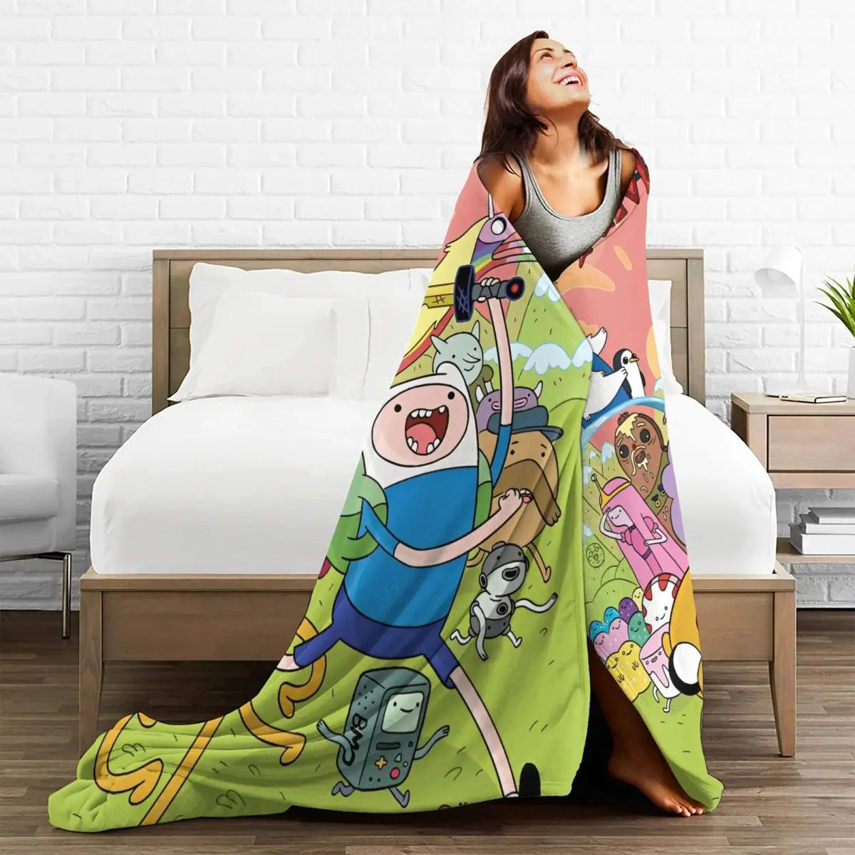 A woman smiling while lying on a bed with an adventure cartoon throw blanket featuring characters like Buzz Lightyear and oth