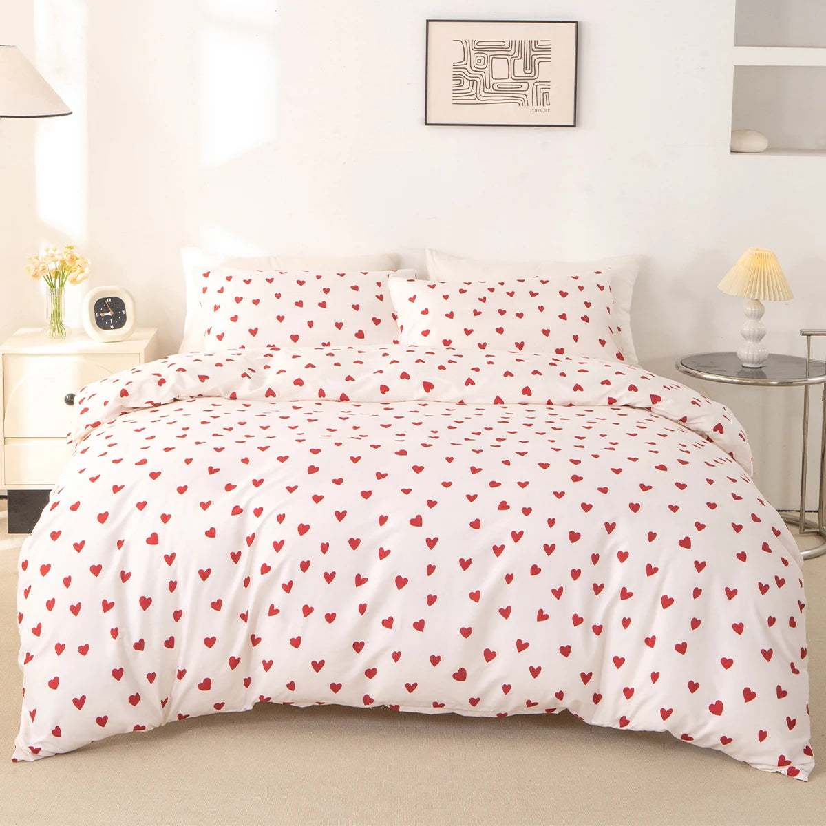 White duvet cover and pillow cases with a red heart print on a bed.