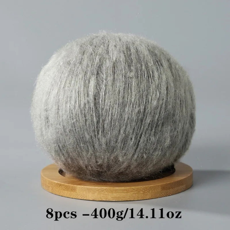 A spherical ball of gray mohair yarn resting on a wooden base.