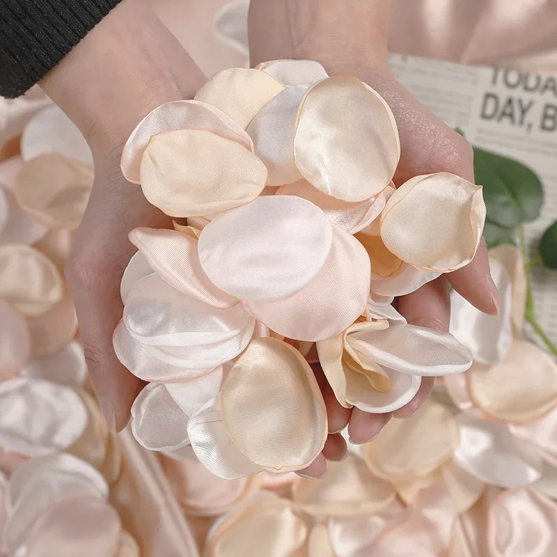 A hand holds a cluster of light pink silk rose petals for weddings and events.