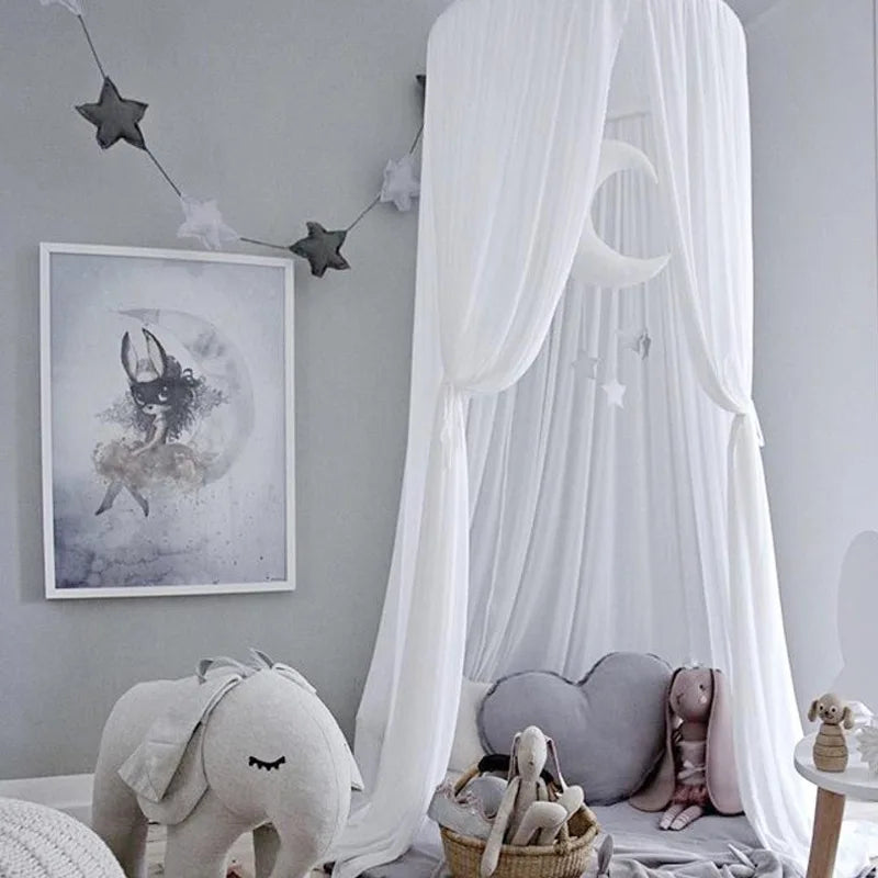 A white pink princess canopy mosquito net for kids with a heart-shaped decoration and stuffed animals.