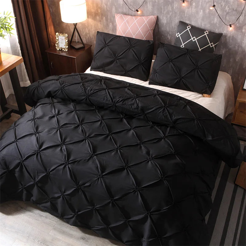 Black quilted duvet and pillows on a bed with pink accent pillows in a bedroom setting.