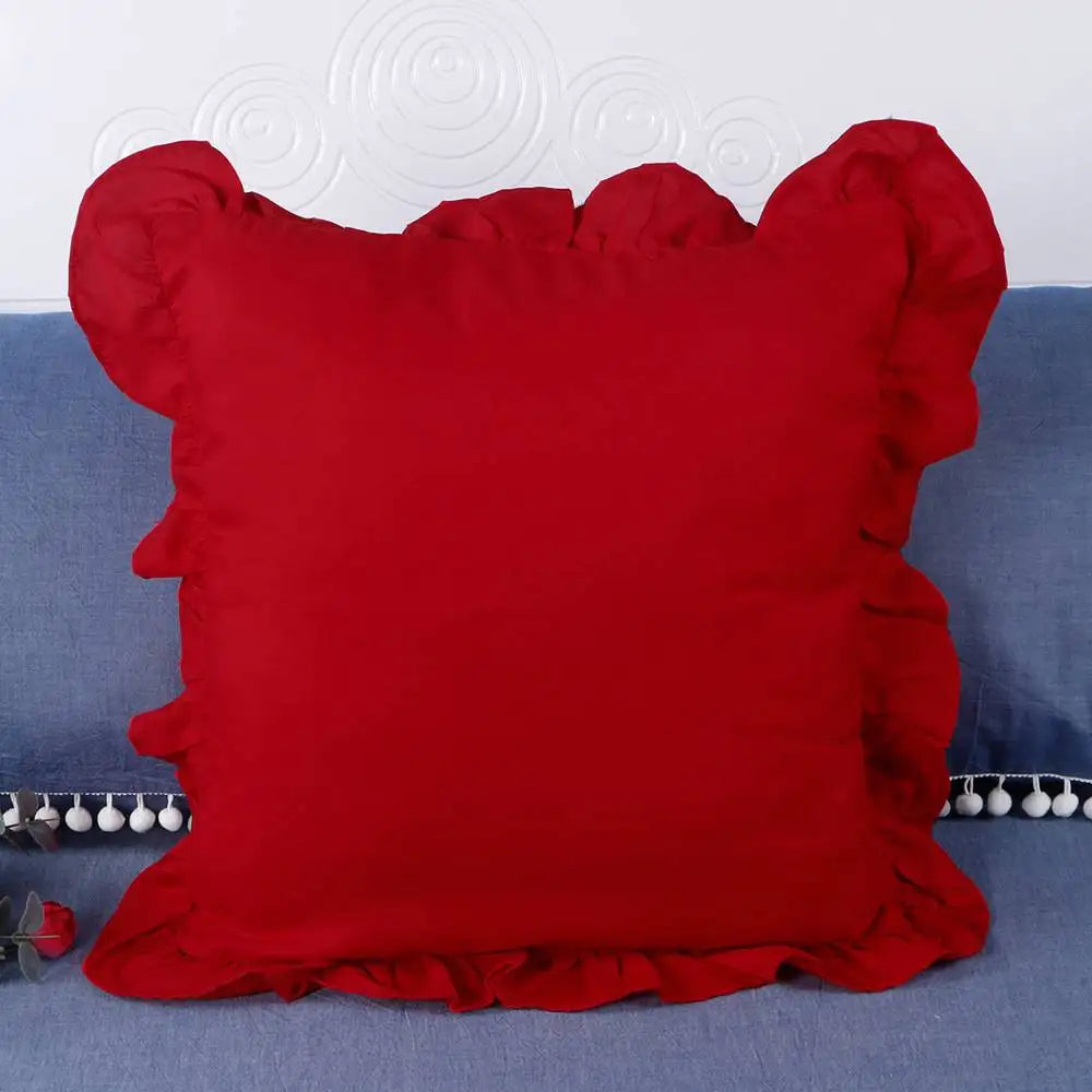 A bright red farmhouse ruffled pillow cover displayed on a blue fabric background.
