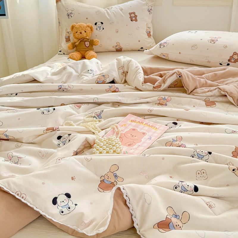 A light pink and cream quilted blanket featuring cute bear and mouse patterns, folded on a bed.