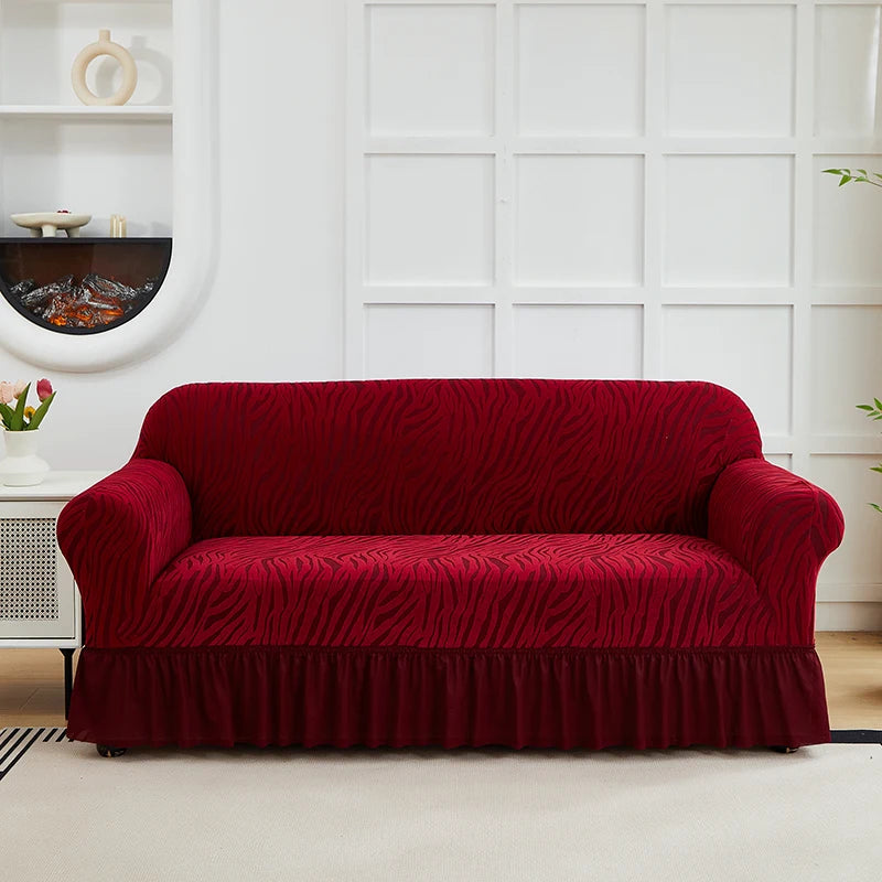 A deep red anti-slip jacquard sofa slipcover placed on a light rug in a bright room.