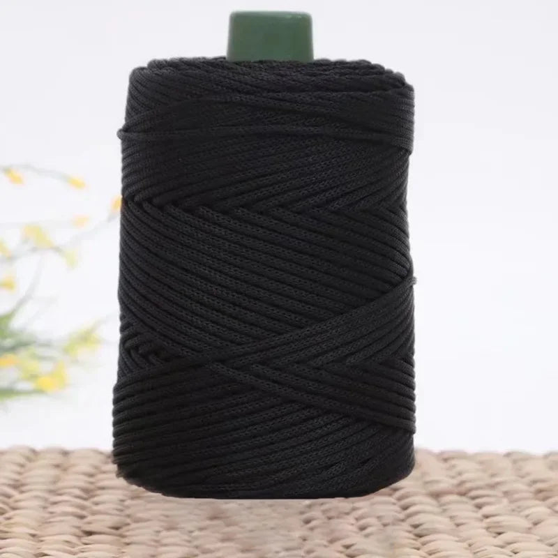 A spool of black 3mm ice rope crochet yarn for crafting with a green cap.
