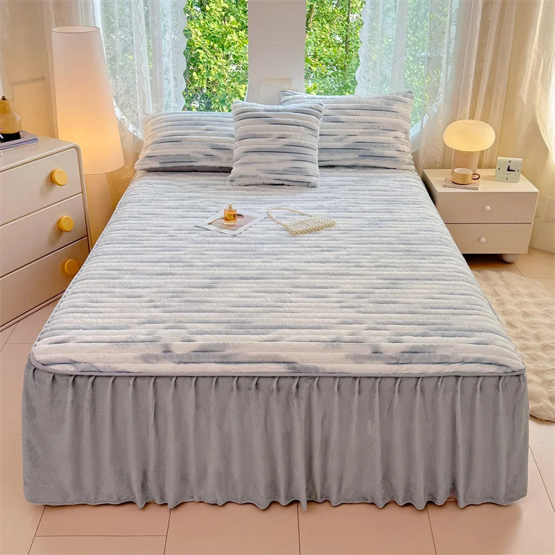 A plush bed skirt linen set featuring light blue and white striped bedding on a bed in a bright room.