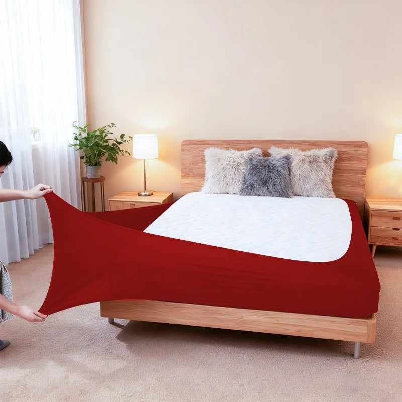 A red high-stretch elastic box spring cover is displayed on a wooden bed frame with fluffy pillows.