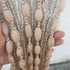 Close-up of beige glitter fringe door curtain strands being held by a hand.