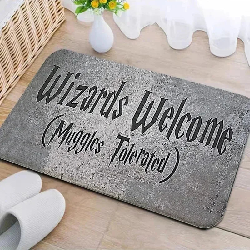 A gray entrance mat with the text Wizards Welcome Muggles Tolerated carved into it, placed on a wooden surface.