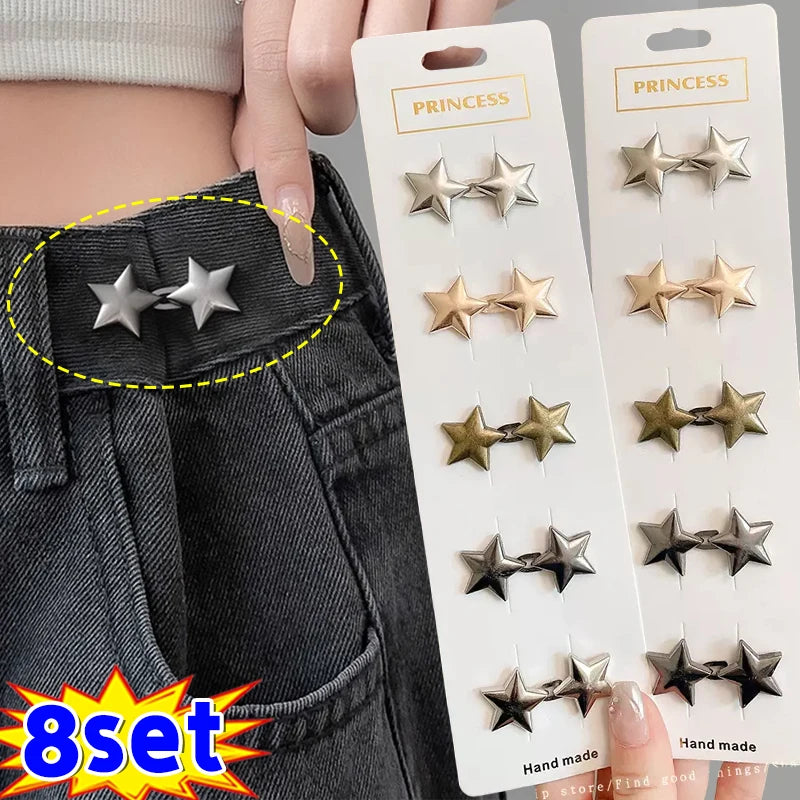 A set of eight adjustable metal star brooch pins displayed on a white card against a dark denim background.