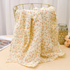 A light yellow floral patterned cotton crib sheet draped over a gold wire hanger.