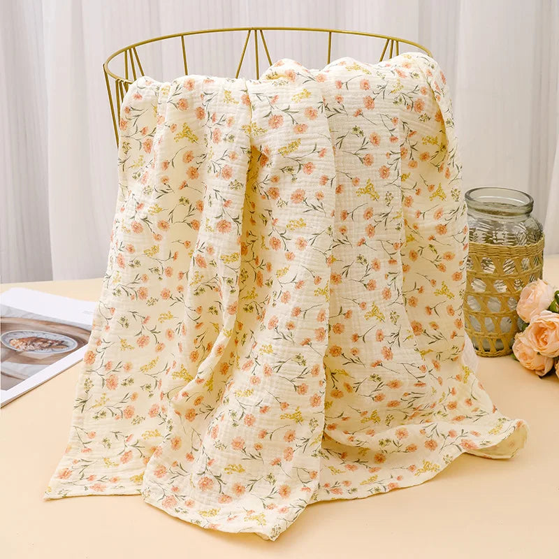 A light yellow floral patterned cotton crib sheet draped over a gold wire hanger.