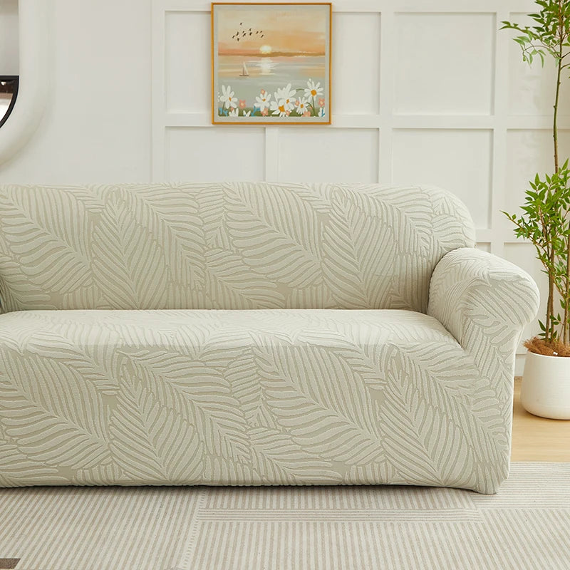 A beige sofa slipcover featuring a woven jacquard leaves pattern in a light neutral tone.