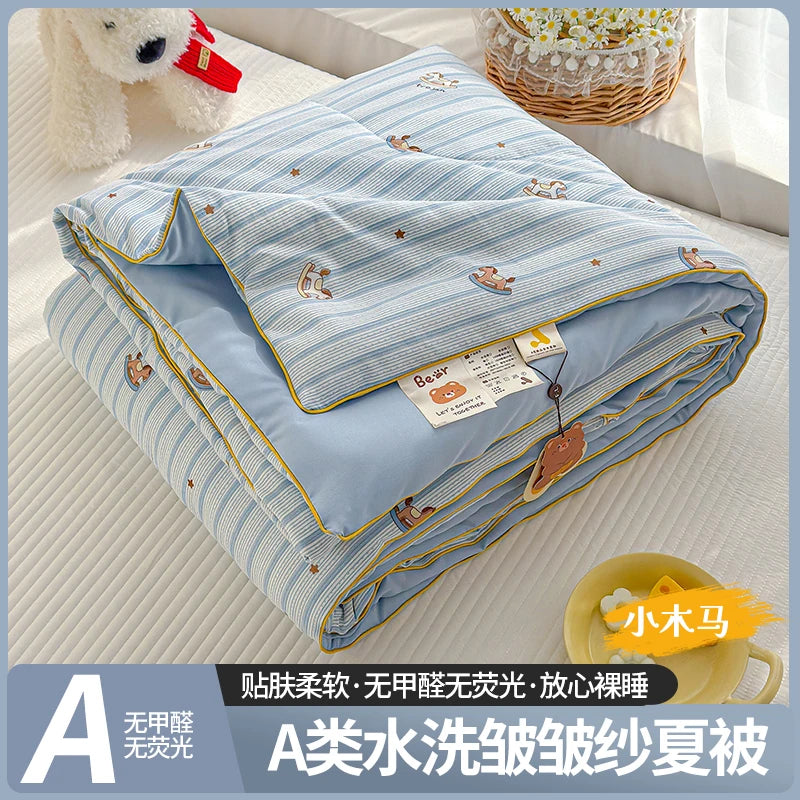 A blue and white striped lightweight quilt with a bear pattern is shown folded on a white surface.