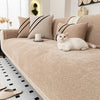 A beige chenille sofa protector cover with striped pillows and a white cat resting on the fabric.